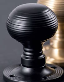 Black door knobs on rose, part of the Till and Whitehead range of architectural ironmongery