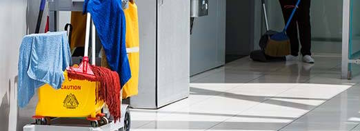 Janitorial products on a trolley with a cleaner preparing for floor care